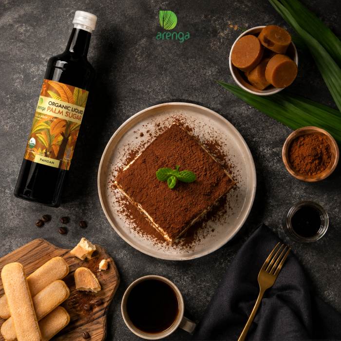 Foto tampak atas tiramisu gula aren dengan cocoa, kopi, gula aren, ladyfinger, dan produk Arenga Liquid Palm Sugar dalam suasana premium bernuansa gelap.
